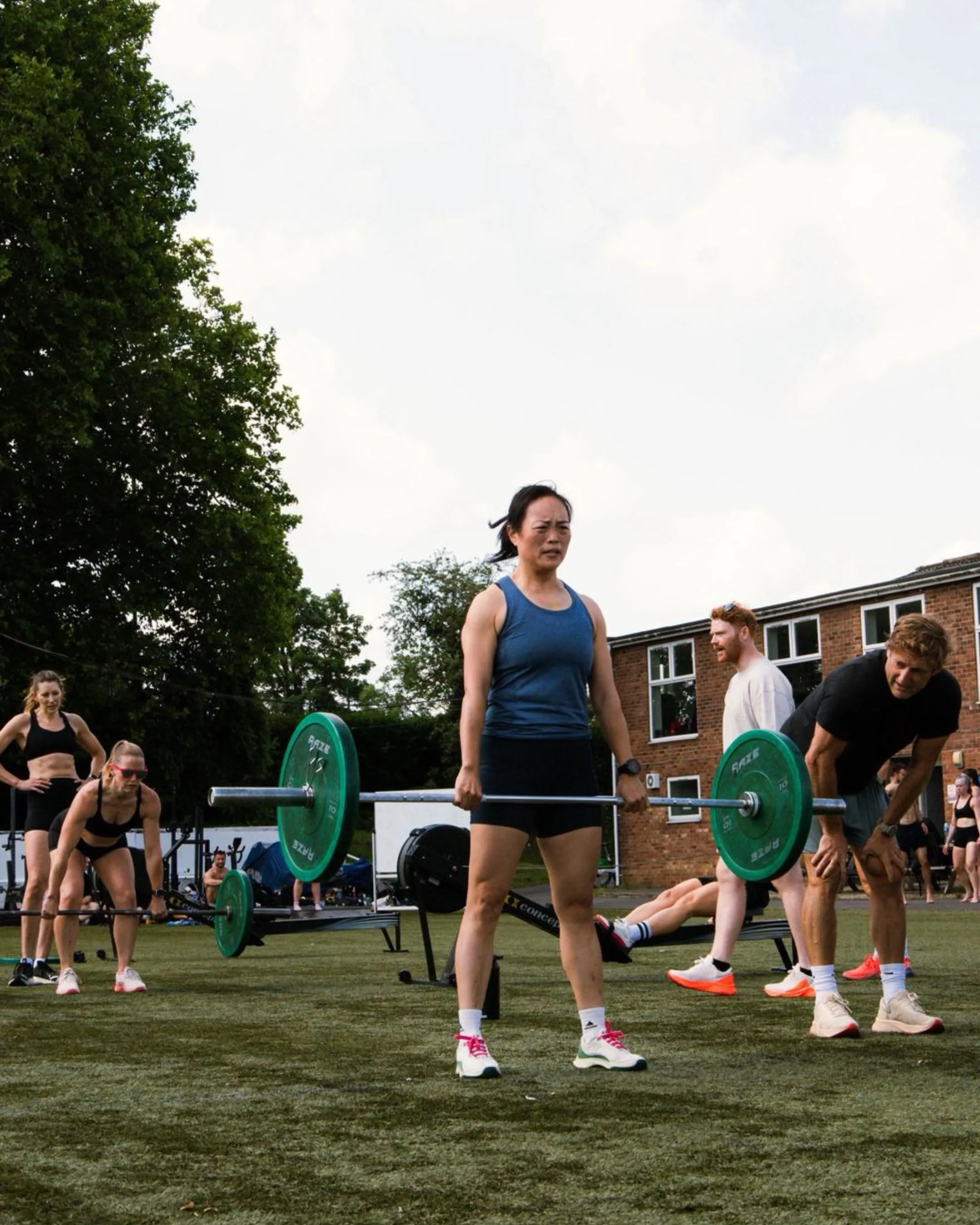 A class working through barbell stations on the pitch